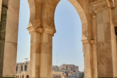 The high engraved arches of the mosque in Casablanca frame a woman walking just outside the arches.