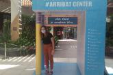 A woman poses under an arch from the Arribat shopping center advertising the center. 