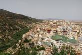 The small city of Moulay Idriss lies below the camera, nestled among mountains. The green roof of a mosque in the center stands out.