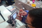 Young boy touches a screen attached to a microscope 