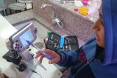 Young girl points to screen attached to a microscope with a pen