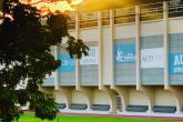 A playing field is in front of the AUD athletics building. The sun is shining over the building and onto the field.