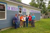 A small group of scholars and volunteers stand in front of a house.