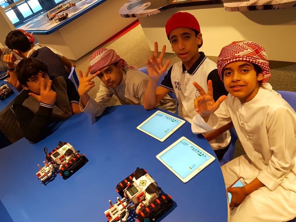 Boys in the Youth English Program in the UAE explore robotics at LEGOLAND Dubai. Kids posing while sitting at a table