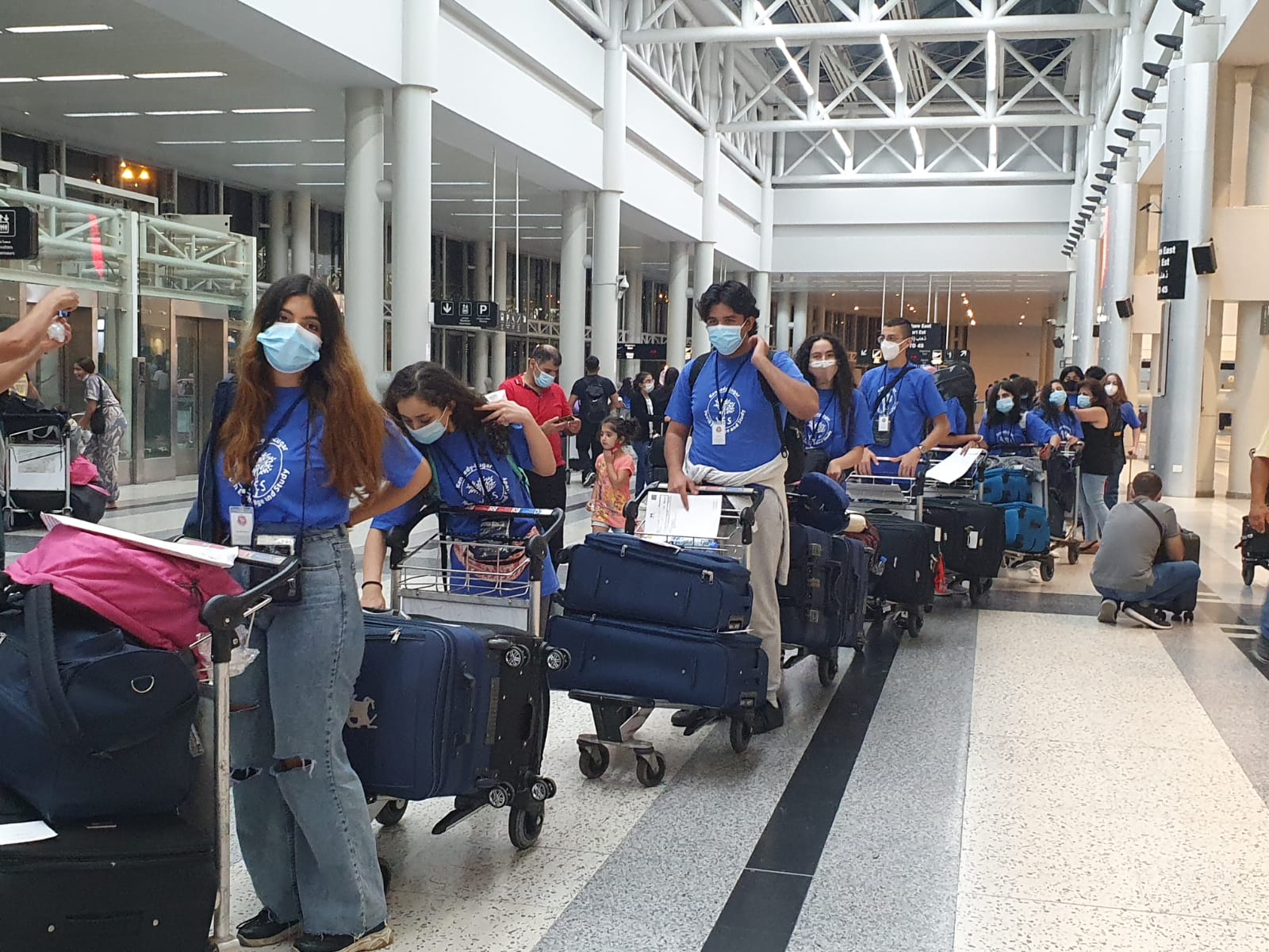 Students moving through the airport with their bags