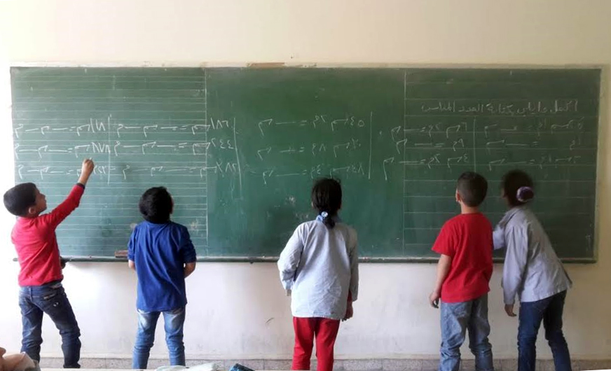 أطفال يكتبون باللغة العربية على السبورة كجزء من مشروع أنا أقرأ