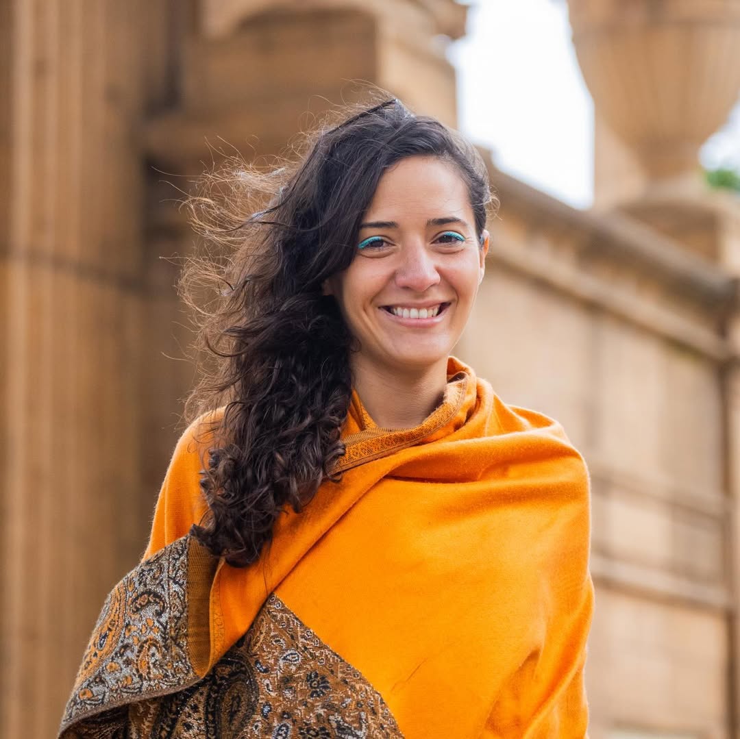 Yasmine in a yellow shawl smiles for the camera