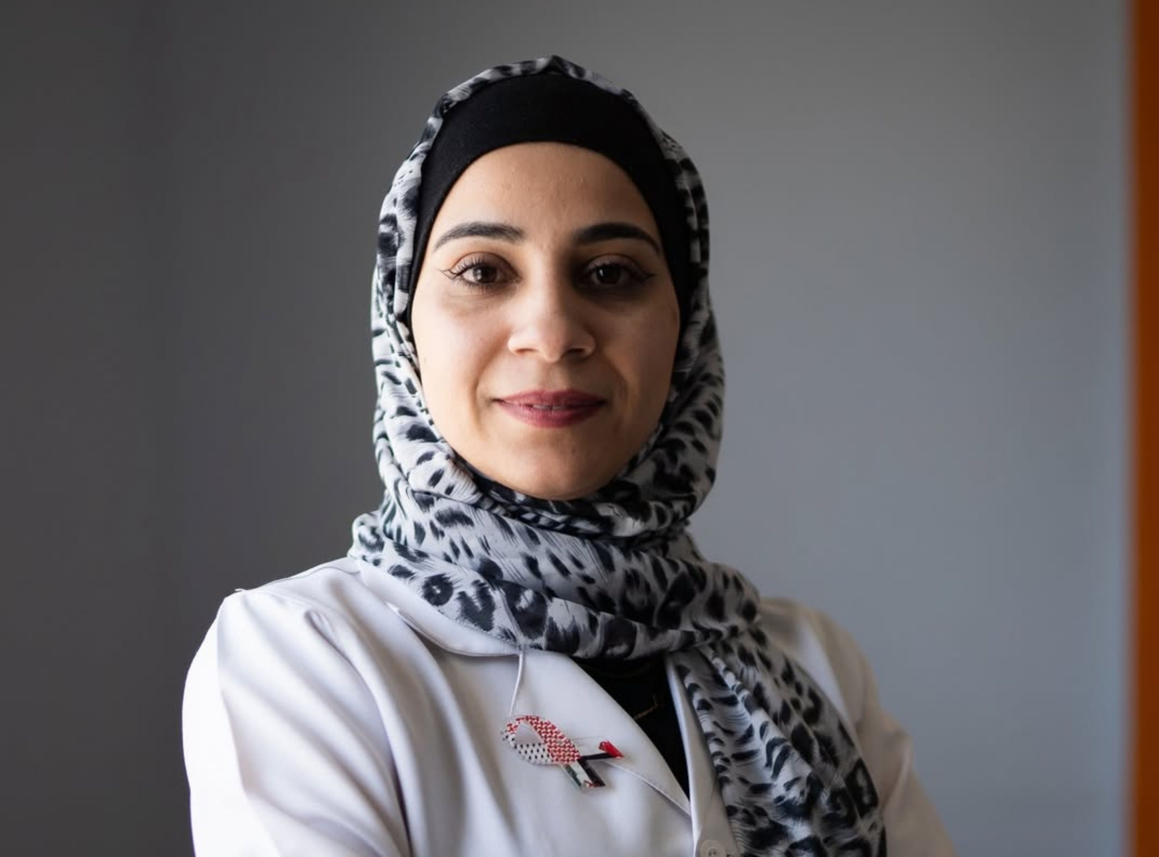 Anoud poses in a medical robe for a headshot