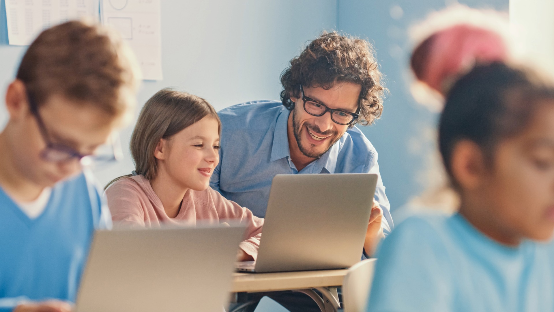 Elementary School Computer Science Class Smart Girl Uses Laptop Computer, Friendly Teacher Helps Her by Explaining Lesson and Assignment. Children Getting Modern Education