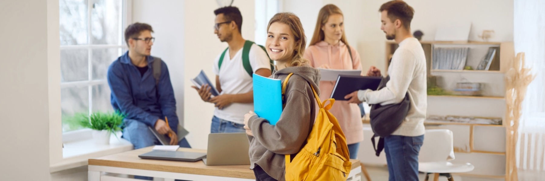 Portrait of smiling millennial Caucasian girl with backpack with groupmates in college or university. Happy young female schoolgirl satisfied with school course or training. Education concept. TOEFL