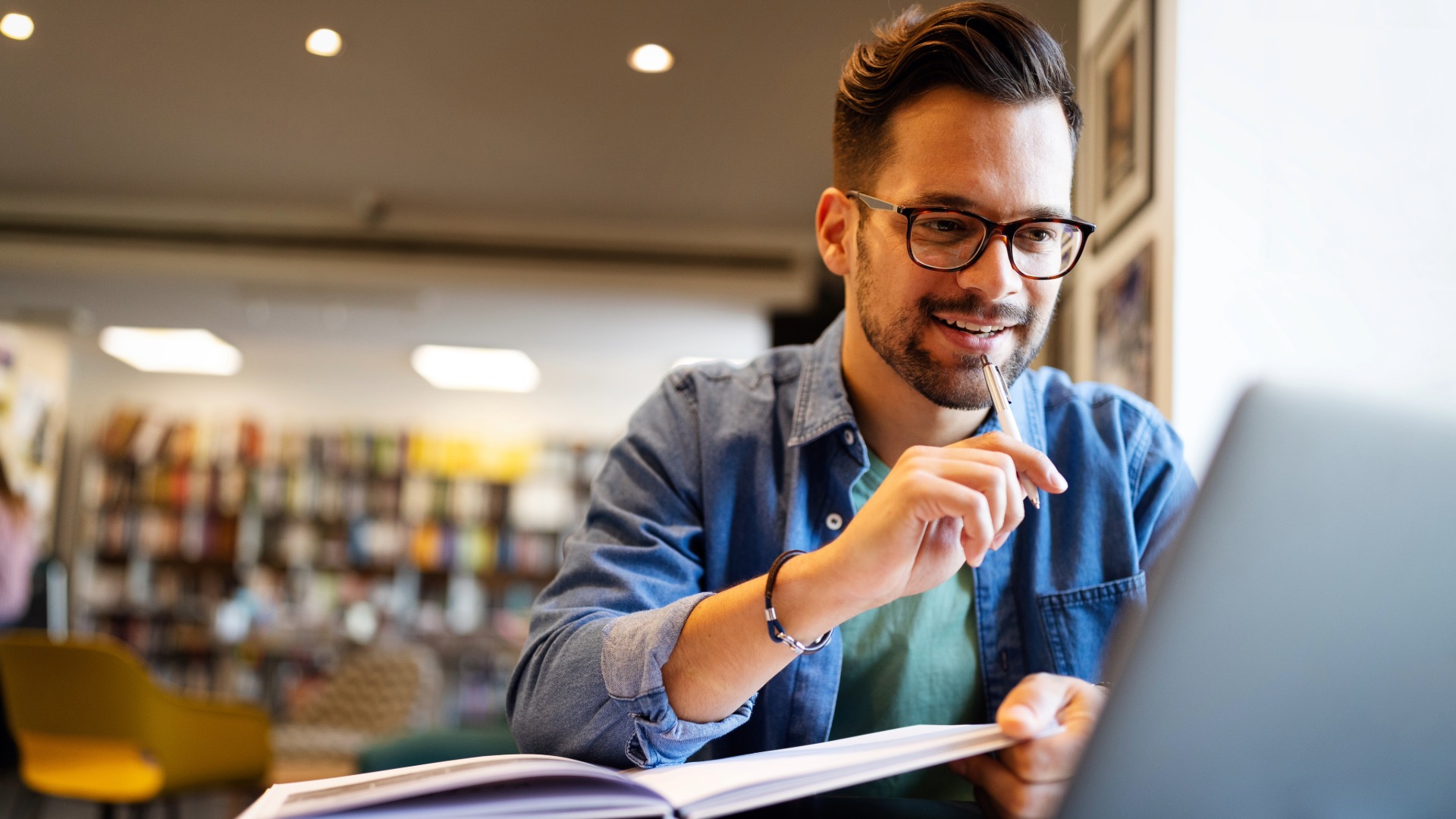 Smiling male student working and studying in a library