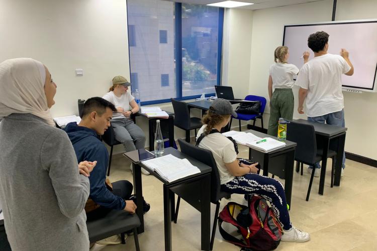 From the teacher's vantage point, two students write on the board in an Arabic class.