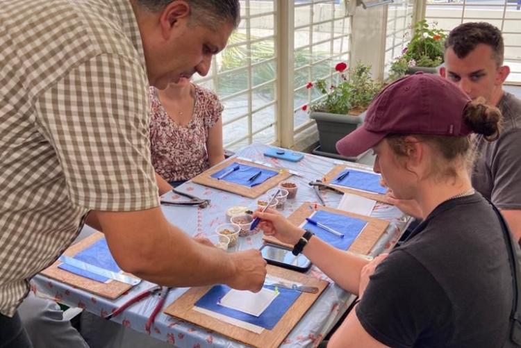 A teacher helps students make mosaics in a semi-outdoor classroom