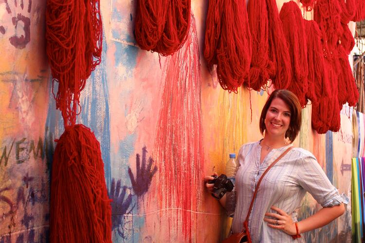 Student standing in Marrakech next to dyed fabric in Morocco