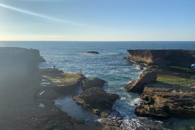 The sun lights up ocean as it comes towards shore among the cliffs in Rabat.