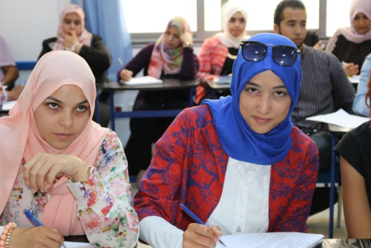 Libyan English teachers write at desks in a classroom during a PCELT training