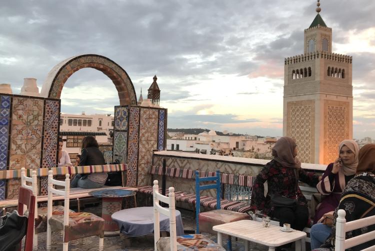 A café overlooks the old medina. A tiled archway and mosque minaret stab the sky.
