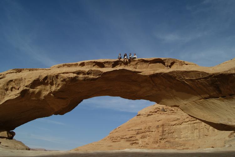 Students sit on a rock bridge in Wadi Rum, Jordan