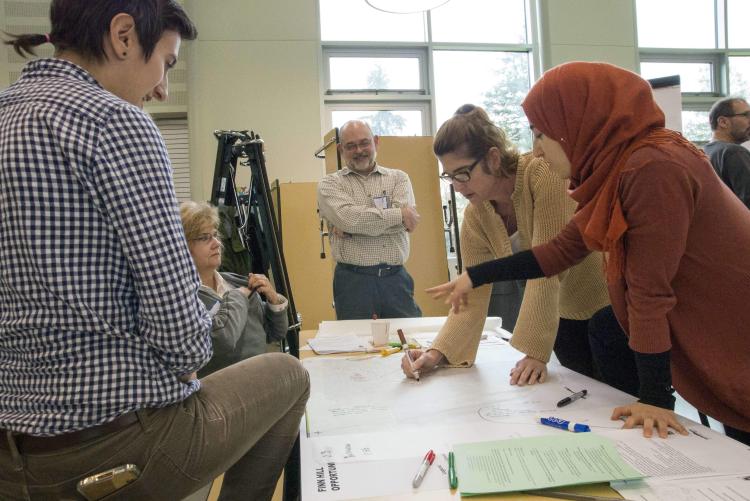 Students in work together over a table in an architecture class 