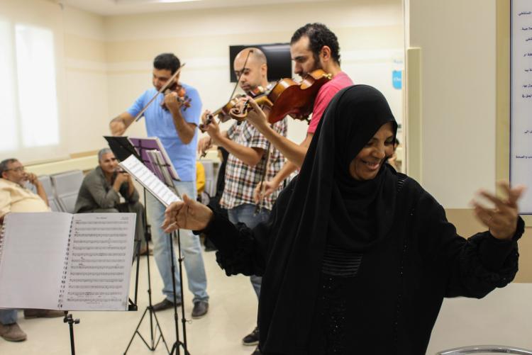 A trio of musician is playing instruments in a hospital. A woman is dancing in the foreground