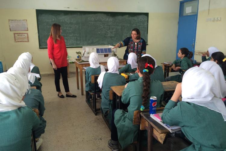 A woman is showing a sustainable model to a classroom of girl