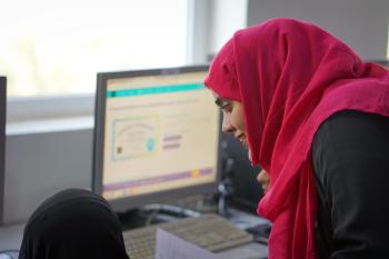 AMIDEAST Yemen Training Coordinator is helping a female Tawtheef recipient while doing an assignment on her computer.