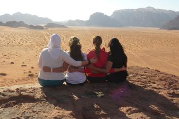 Four women sit on a rock in Wadi Rum, Jordan