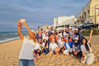 One individual takes a selfie with a group on the beach in Tangier