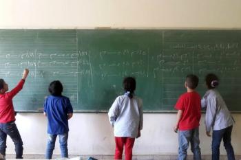 Children writing in Arabic on a blackboard as part of the Ana Iqra project