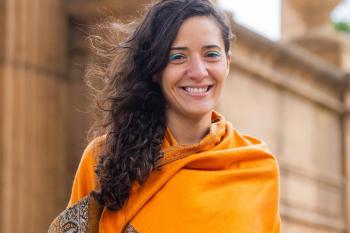Yasmine in a yellow shawl smiles for the camera