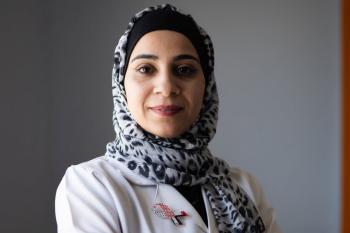 Anoud poses in a medical robe for a headshot
