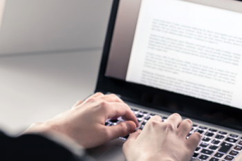 Student writing with laptop. 