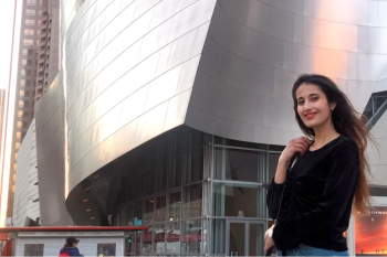 Woman with silver building behind her.