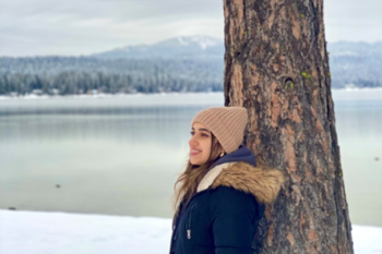 Woman leaning against a tree.