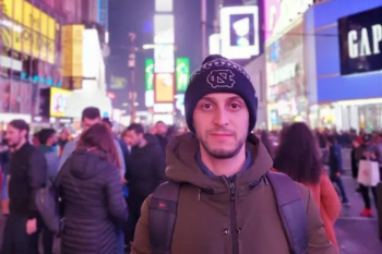 Man standing in Times Square at night.